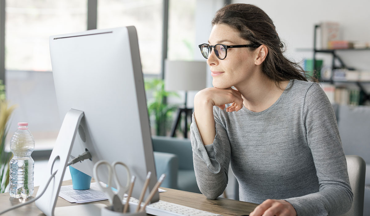 Person sat at desk looking at computer monitor Person sat at desk looking at computer monitor