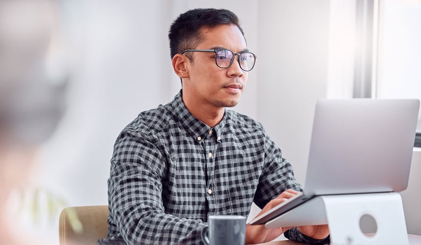 Person sat at desk looking at a computer Person sat at desk looking at a computer