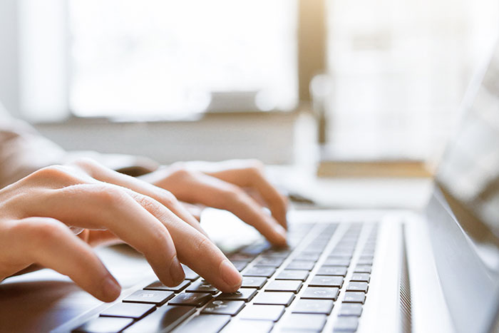 Close up image of hands typing on a keyboard Close up image of hands typing on a keyboard