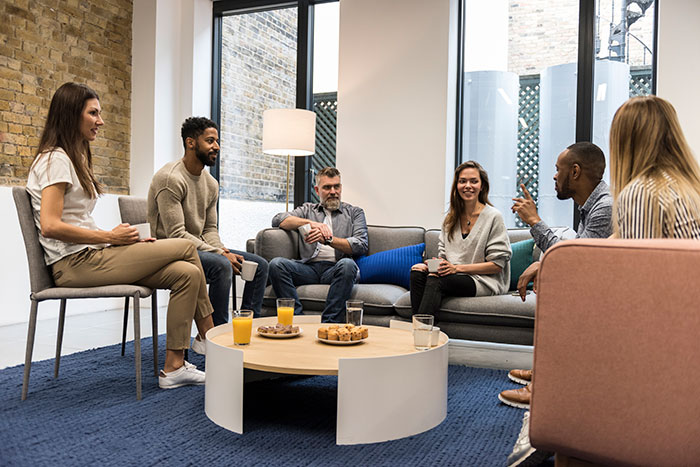 Group of people sat around a small table having a discussion Group of people sat around a small table having a discussion