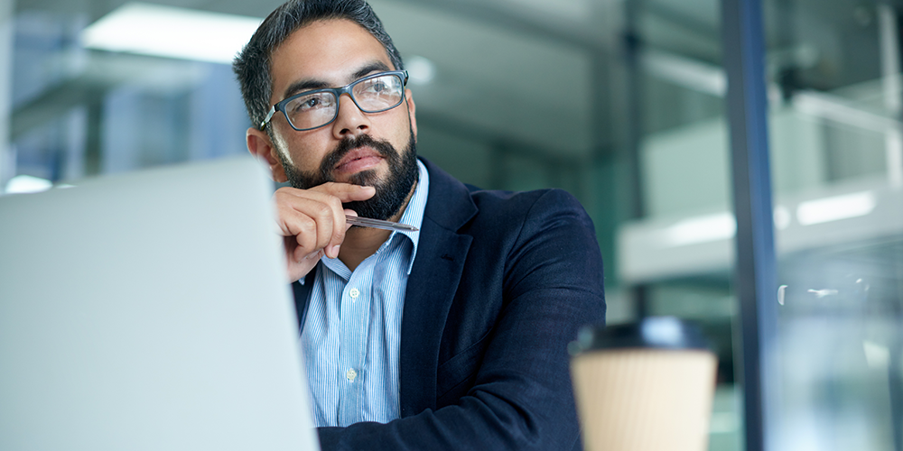 Man thinking in front of a laptop Man thinking in front of a laptop