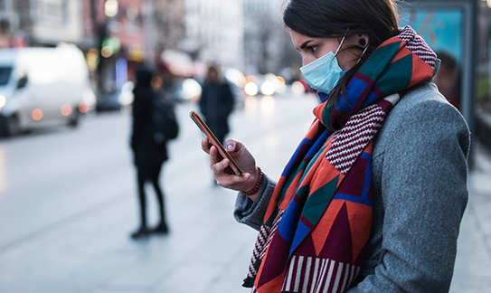 Woman wearing medical mask looking at her phone Woman wearing medical mask looking at her phone